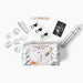 The Beloved Vacation Lovin' Intimacy Kit features a silver cosmetic bag with travel perfume spray, condoms, flower petals, a lipstick-sized item, "Love Potion" tube, and a card reading "SEX," perfect for sensual getaways.