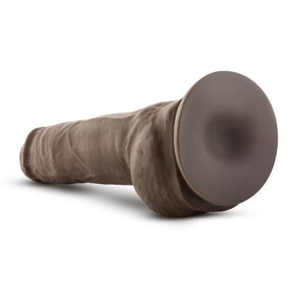 The Big Boy Huge 10 Inch Dual Density Dark Tone Suction Cup Dildo, shown lying on a white background, features a realistic look and feel with dual density design and a sturdy suction cup base.