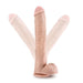 A realistic-looking Blush Big Daddy 14 Inch Dual Density Suction Cup Dildo - Vanilla is shown, featuring a flesh-toned design with testicles and a suction cup base. The image illustrates the flexibility of the dual density dildo, with two ghosted versions of it bent in different directions.