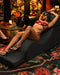Relaxing in style: a person unwinds on an opulent Liberator Aria Chaise Sex Lounger, surrounded by luxurious decor and a touch of candlelight ambiance.