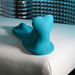 The Bumps & Grind Triple Bump Flexible Grinding Vibrator, a blue silicone personal massager with a curved shape and flexible pleasure pad, sits on white leather with a textured blue background.