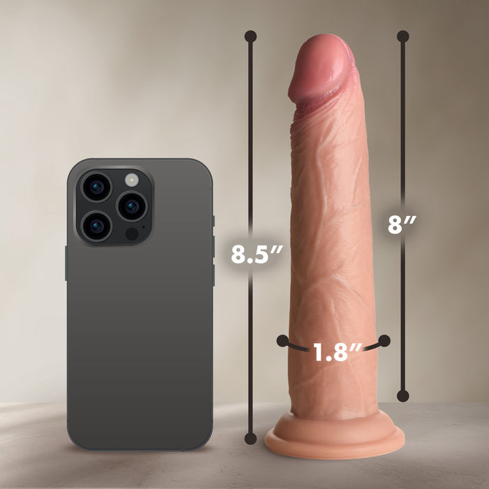 The Jock Real Skin 8.5 Inch Silicone Suction Cup Dildo in Caramel, with lifelike texture, stands upright beside an 8.5-inch smartphone on a neutral background, highlighting its realistic size and sturdy suction base.