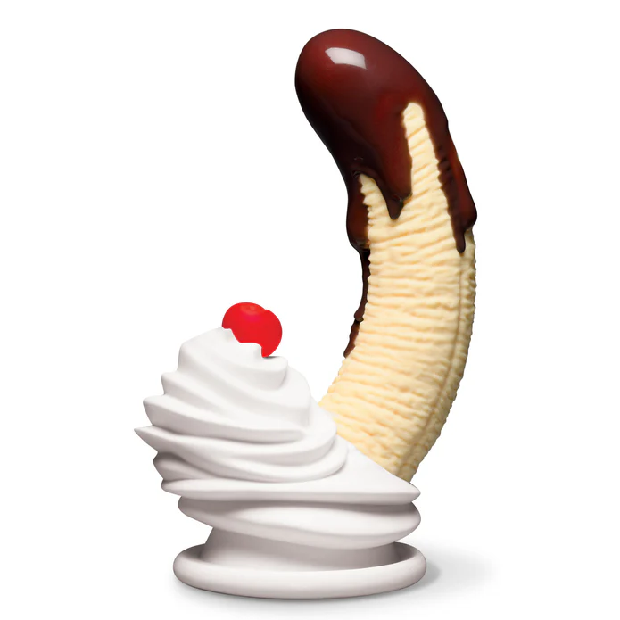 The Chocolate Dipped Banana Split Silicone Dildo, designed to look like a peeled banana dipped in chocolate, stands upright beside a swirl of whipped cream and a cherry on top, all set against a white background.