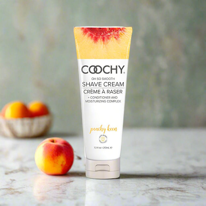 A 7.2 fl oz (213 mL) tube of Coochy Oh So Smooth Shave Cream - Peachy Keen, featuring vibrant peach imagery and a moisturizing complex for smooth skin.