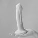 A hand holds an upright bottle of Creamy Glide Milky Semen-Style Cum Lubricant (8.5 fl oz), with the smooth, creamy liquid dripping down its side. The background is plain and softly blurred in this black and white image.