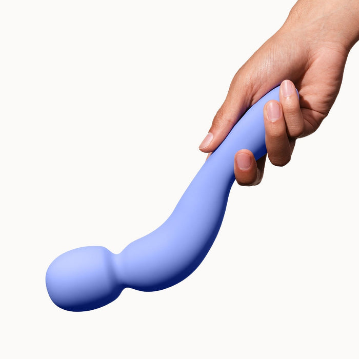 A hand holds the Dame Com Ergonomic Waterproof Wand Vibrator with Flexible Neck—its blue, curved design and bulbous end promise deep, rumbly vibrations for intense clitoral pleasure—set against a plain white background.
