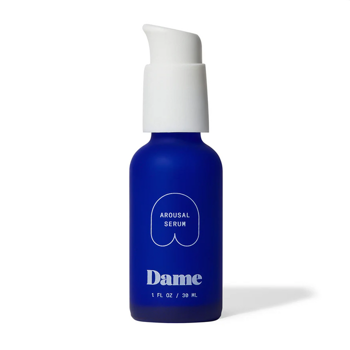 A blue bottle with a white pump labeled "Dame Lickable Clitoral Arousal Serum 1 oz" sits against a plain white background, containing a natural formula designed for clitoral stimulation.