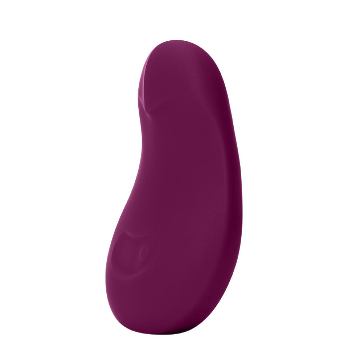 The Dame Pom Hand Held Flexible Vibrator in Plum is a small, curved, waterproof, medical-grade silicone toy with a smooth surface and ergonomic design, shown standing upright against a white background.