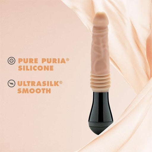 A Dr. Knight Vibrating Thrusting Gyrating Realistic Silicone Dildo - Vanilla by Blush, featuring a lifelike design and black handle, is showcased against a soft pink background. Text adjacent to this body-safe toy reads "PURE PURIA® SILICONE" and "ULTRASILK® SMOOTH." The backdrop exhibits a flowing fabric-like texture in gentle pastel hues.