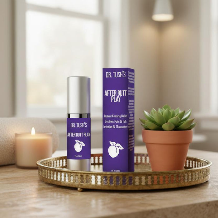 A bottle and box of Dr. Tush's After Butt Play Soothing Lotion rest on a gold tray beside a small potted succulent, set against a softly lit living room backdrop.