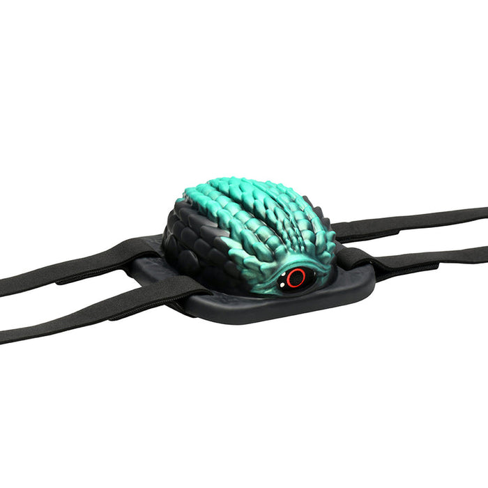 A black and teal, dragon scale-patterned eye mask with a central red eye and side black straps, inspired by the Dragon Grinder - Vibrating Silicone Fantasy Pad, displayed on a white background.