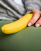 Banana Emojibator Vibrator held in woman's hand against her green pants 