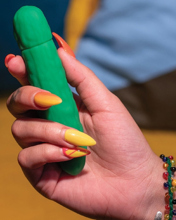 Pickle Emojibator Vibrator in model's hand with yellow nail polish 