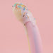 A pastel Fantasia Smooth 7 inch Glow in the Dark Silicone Dildo with Suction Cup is coated in white icing and colorful sprinkles, set against a pink background.