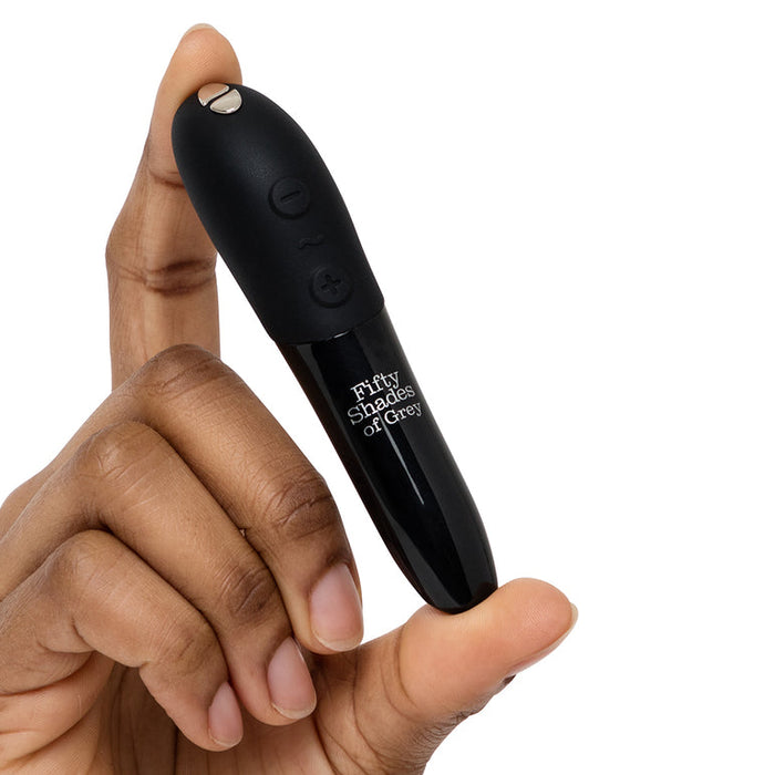 A hand holds a sleek black device labeled "Fifty Shades of Grey Come to Bed Kit," bullet-shaped with buttons, set against a plain white background—an ideal addition to any premium pleasure collection.