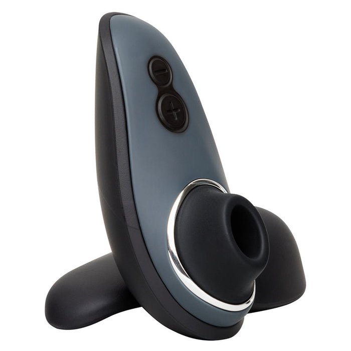 The Fifty Shades of Grey Desire Blooms Kit is a gray and black handheld clitoral stimulator with a circular front opening, plus and minus buttons on top, a silver rim, and an upright flat base.