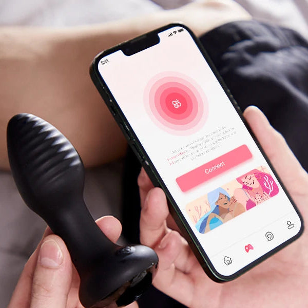 A person holds the Frenzy Pressure Sensing App-Controlled Butt Plug in one hand and a smartphone in the other, displaying an app with a pink "Connect" button and an illustration at the bottom.
