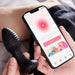A person holds the Frenzy Pressure Sensing App-Controlled Butt Plug in one hand and a smartphone in the other, displaying an app with a pink "Connect" button and an illustration at the bottom.
