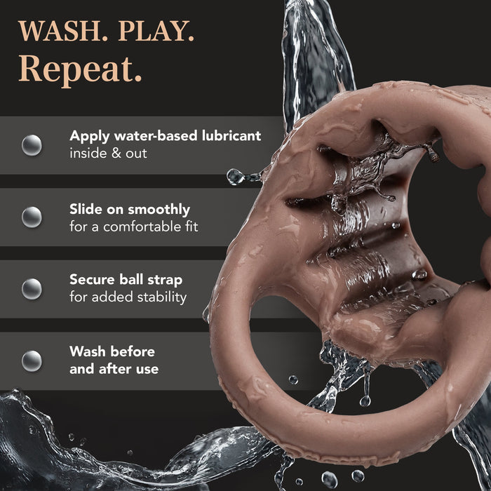 The Girthy Pleasure Sleeves - Open-Ended Silicone Penis Sleeve (Size M) is shown splashed with water. Instructions: "Apply water-based lube, slide on, secure ball strap, wash before & after use." Heading: "WASH. PLAY. Repeat.