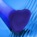 Close-up of the Glow Light Up Blue LED 7 Inch Silicone Dildo, featuring a heart-shaped base, small charging indicators, and LED glow. Its purple silicone design is strap-on harness compatible, set against a blue, glass-textured background.