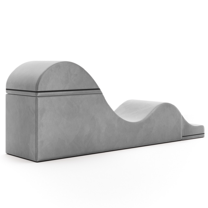 The Liberator Aria Flip Chaise Sex Lounger is a gray, modern, convertible bench with a wave-like design and smooth surface, discreetly blending into the bedroom against a plain white background.