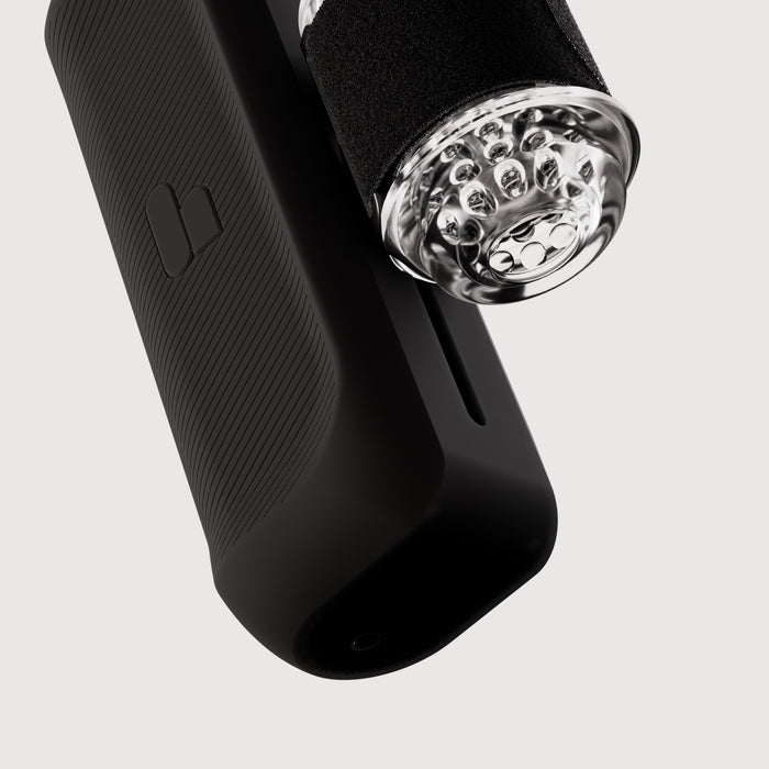 Close-up of The Handy 2 Interactive Automatic Masturbator, sleek and black with a transparent, textured cylindrical attachment featuring bubble-like details, set against a plain white background.