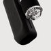 A close-up of The Handy 2 Interactive Automatic Masturbator, a black textured device with a transparent cylindrical attachment featuring multiple small round parts inside, shown against a plain white background.