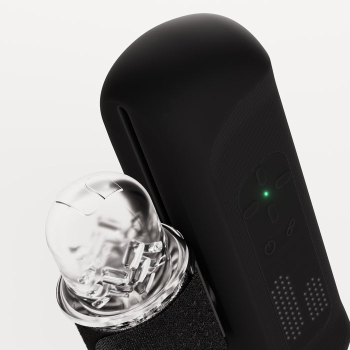 Close-up of The Handy 2 Interactive Automatic Masturbator, featuring a green indicator light and a transparent, rounded attachment that reveals internal components, set against a white background.