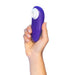 A hand holds the Womanizer Starlet 3 Pleasure Air Clitoral Stimulator, a compact purple oval device with a white circular opening, against a white background.