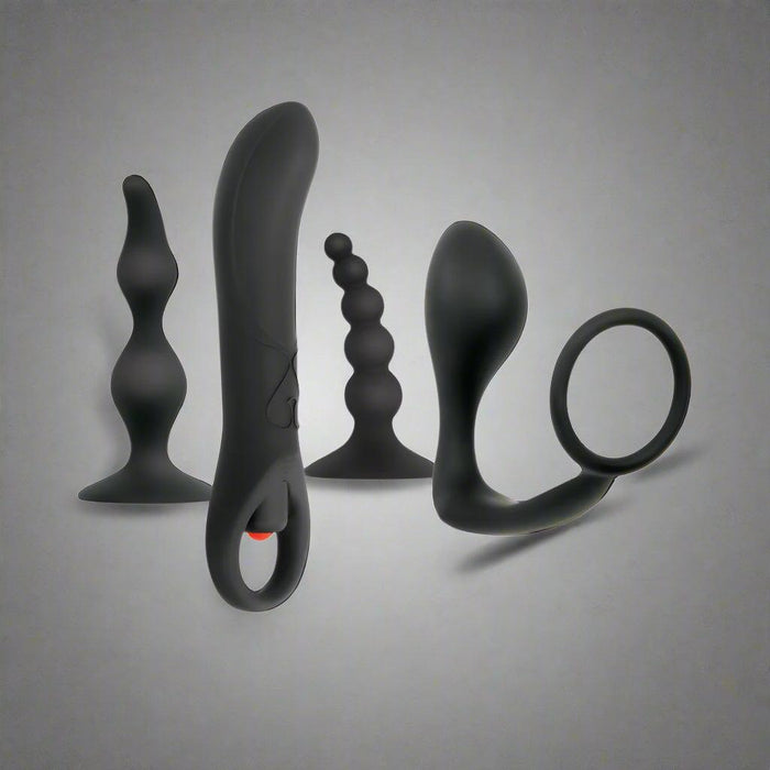 The Intro To Prostate Kit 4 Piece Silicone, featuring four black silicone anal toys—a beaded plug, curved massager, textured plug, and ringed plug—is displayed upright against a plain gray background.