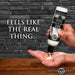 A person dispenses creamy Jizz Ultra Realistic Unscented Cum Lube from a black and white bottle onto their palm. The background features a dark brick wall with the text "FEELS LIKE THE REAL THING..." displayed.