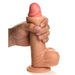 A hand grips the Jock Real Skin Thick 8 Inch Light Tone Silicone Suction Cup Dildo with Balls, featuring lifelike texture and realistic details, against a white background.