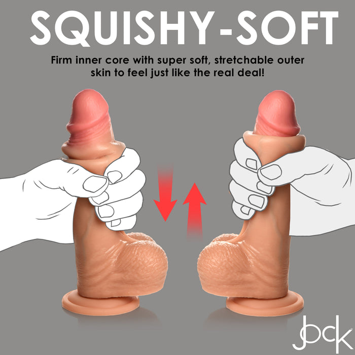 Hands squeeze the Jock Real Skin Thick 8 Inch Light Tone Silicone Suction Cup Dildo with Balls, showing its lifelike texture and flexibility. Red arrows highlight stretch, while text notes the soft outer skin and firm inner core for realism.