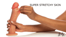 A hand stretches the outer skin of the Jock Real Skin Thick 8 Inch Light Tone Silicone Suction Cup Dildo, showing off its flexible, stretchy material. The words "SUPER STRETCHY SKIN" appear in the top right corner.