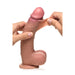 The Jock Real Skin Thick 9 Inch Medium Tone Silicone Suction Cup Dildo with Balls is being stretched by two hands, showcasing its flexible, textured skin and detailed features.