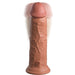 The King Cock Elite Thick 8 Inch Vibrating Dual Density Medium Tone Silicone Dildo stands upright, featuring a realistic veined texture and motion-blurred tip that suggests vibration for an authentic experience.