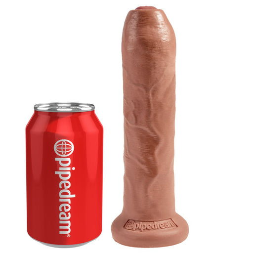 The King Cock Uncut 7 Inch Medium Tone Suction Cup Dildo with Moving Foreskin stands upright next to a red "pipedream" soda can, clearly showing the size comparison between the realistic toy and the can.