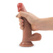 A hand holds the Kona Ultra Realistic 7.5 Inch Silicone Dildo with Suction Cup, a flesh-toned, poseable dildo, against a white background.