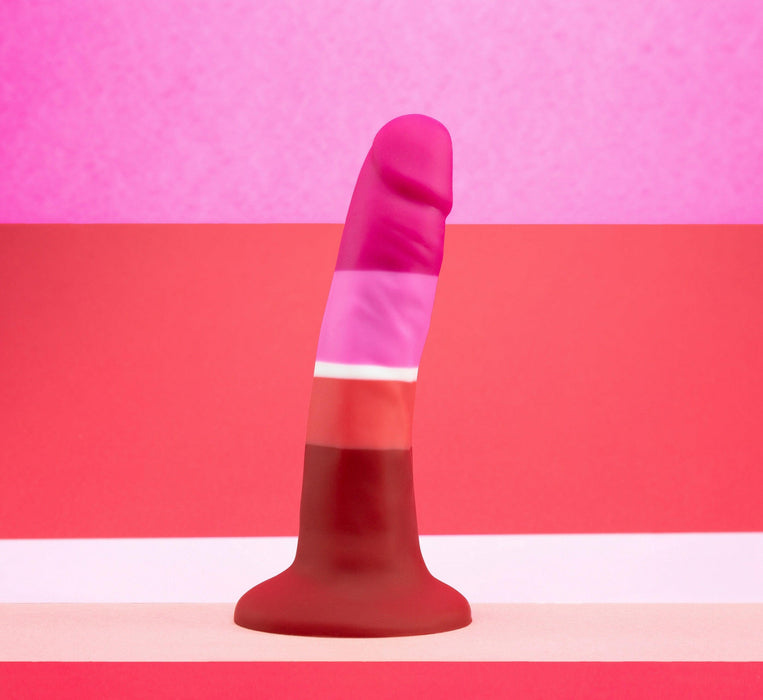 The Lesbian Pride Small 5.5 Inch Silicone Suction Cup Dildo, in pink, red, and maroon, stands upright against horizontal bands inspired by the Lesbian flag.