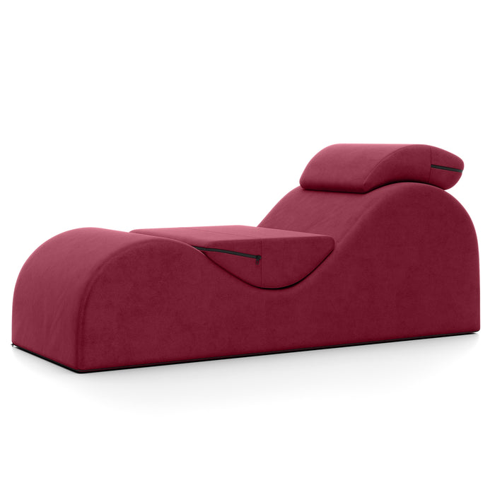The Liberator Esse Sex Lounger features a modern, burgundy design with ergonomic curves, a built-in headrest, and two zippered side compartments. It sits on a flat black base, showcased against a white background.