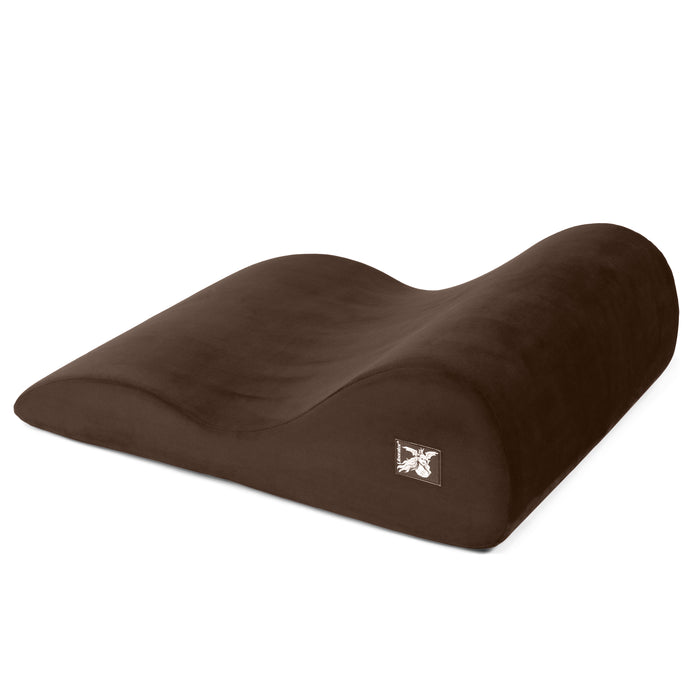 The Liberator Hipster Intimate Positioning Support Sex Cushion is a brown, contoured foam pillow with a wave-like shape and small embroidered logo, designed for ergonomic comfort and full-body support.