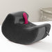 The Liberator Pulse – Ergonomic Straddling Toy Mount in dark gray, featuring a pocket for your favorite toy, sits on a white surface next to a beige nightstand—designed for hands-free intimacy.
