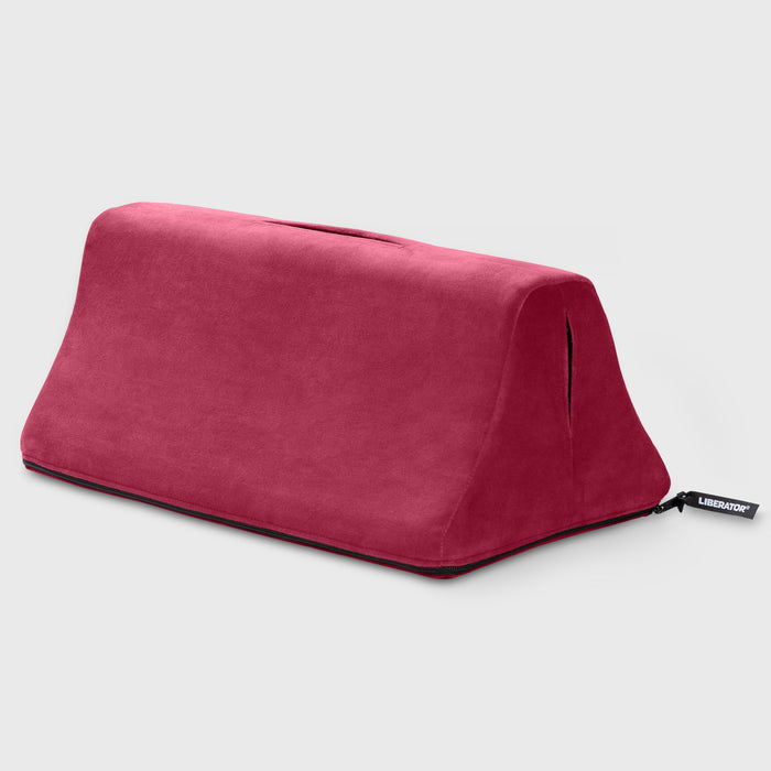 The Liberator Tula – Dual-Toy Sex Cushion for Double the Pleasure is a triangular red wedge with a handle and small black Liberator tag, shown on a plain light gray background.