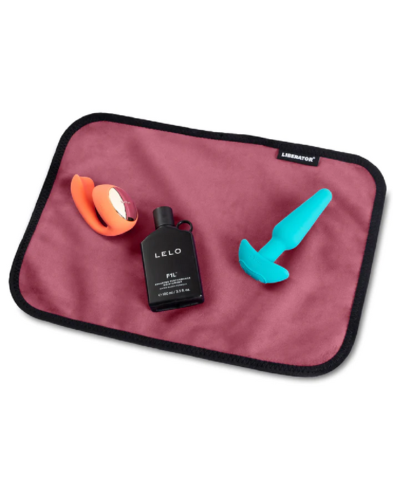 Liberator Fascinator Toy Pad Mini Waterproof Sex Blanket - Merlot with toys and lube on it 