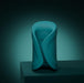 A sleek teal Lovense Gush 2 oscillating masturbator with smooth curves and a circular pattern stands on a dark surface against a gradient teal background, offering modern design and app compatibility for a hands-free experience.