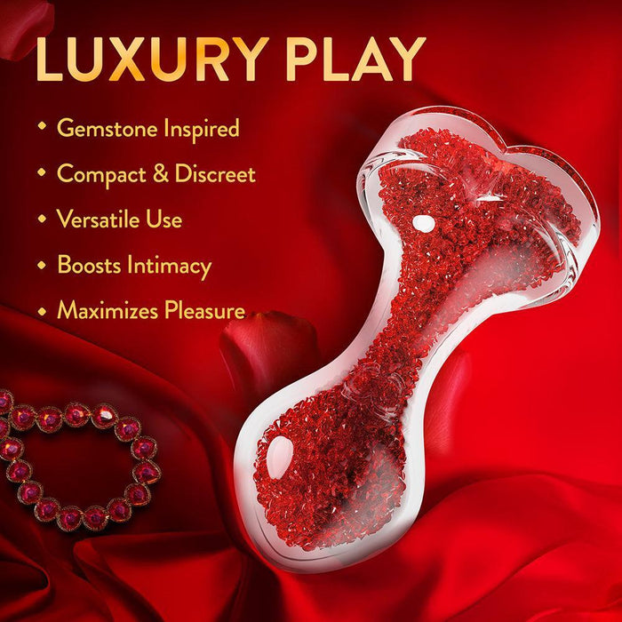 The Lustre Glass Butt Plug with Gem Base & Red Crystals, inspired by gemstones, is compact, discreet, and made of borosilicate glass to boost intimacy and maximize pleasure. It features a heart-shaped base adorned with red crystals.