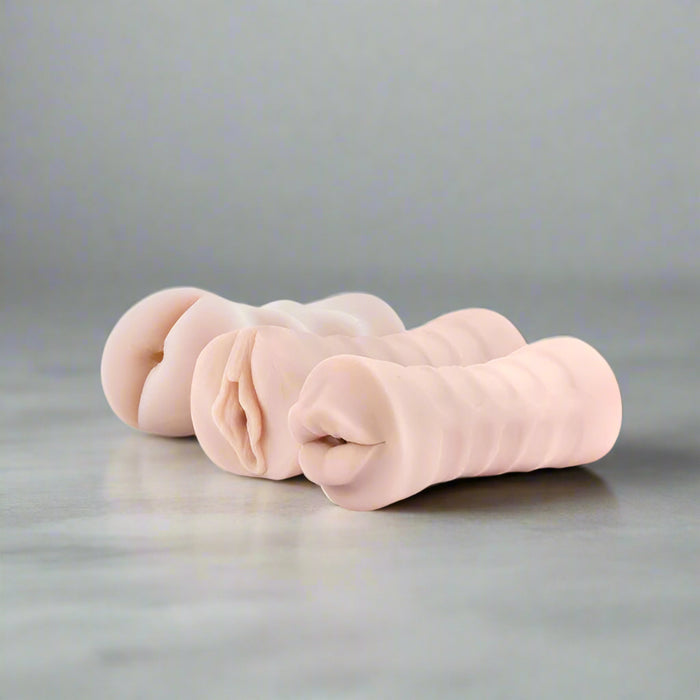 A row of three flesh-colored silicone adult toys, known as the M for Men 3-Pack Self-Lubricating Vibrating Pocket Strokers by Blush, crafted from lifelike X5 material, arranged against a white background. Each device features unique textures and appearances for intimate use.