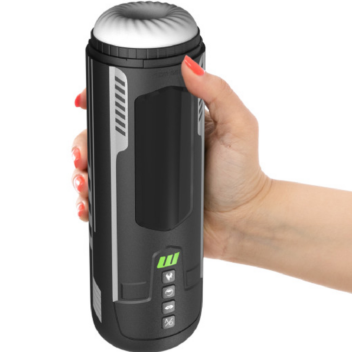 A hand holds The Ultimate Stroke & Relax Bundle, a black electronic automatic stroker with buttons, display screen, rounded white top, and silver accents.