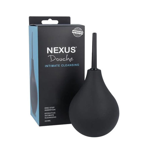 A black Nexus Non Return Valve Anal Douche is displayed in front of its packaging. The text on the packaging reads "Nexus Douche Intimate Cleansing" and "One step insertion effective cleansing, 224ml." The product features a liquid bulb, a non-return valve for safety, and a thin nozzle for application.