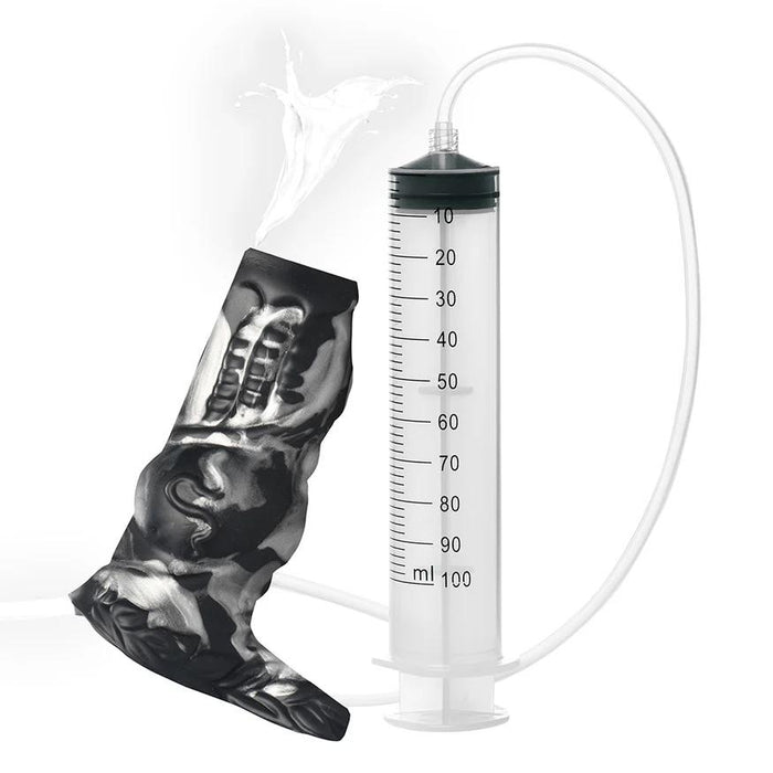 The Night Prowler Squirting Penis Enhancer is shown connected by a tube to an anatomical model, with liquid squirting out the top to demonstrate its use—displayed here as an educational accessory.